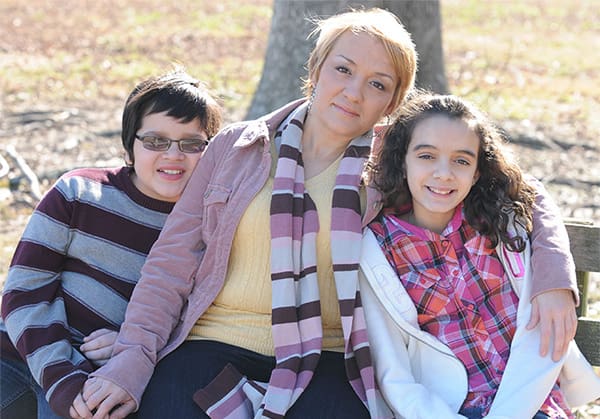 Mother and two children sitting on a bench smiling at the camera